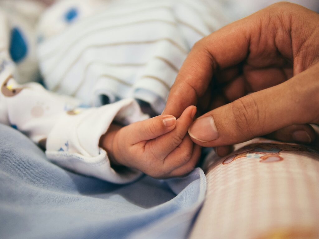 person holding baby's index finger person holding baby's index finger